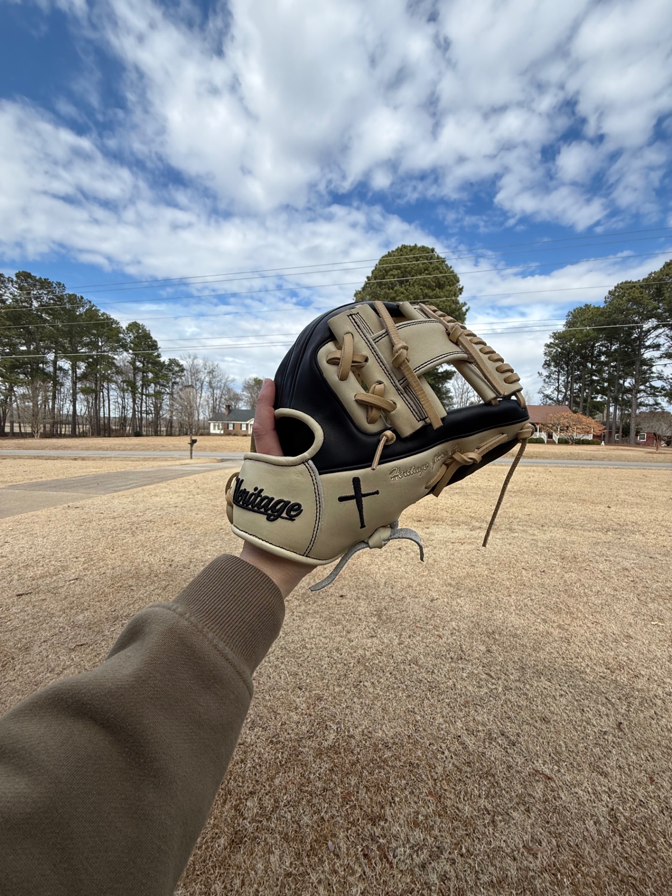 Cream and black Heritage glove with cross under a blue sky
